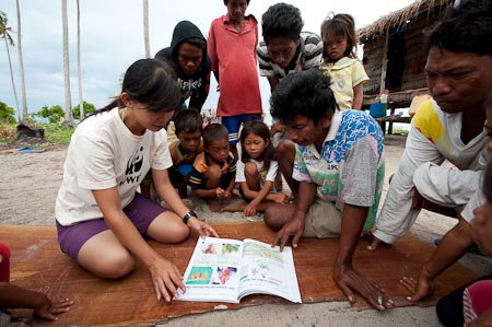 Nina Ho explains to a Bajau fisherman each page of a seaweed book on how to grow carrageen seaweed