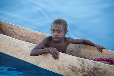 Young Papuan boy in a dugout canoe out at sea