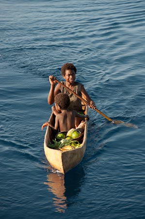 Paddling closer to a dive liveaboard, Papuans in Witu Island barter and trade fruits and vegetables for rice, noodles and soap