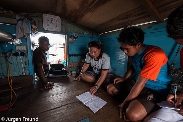 WWF Monitoring team leader Tika reviews fisherman's notebook that contains daily whale shark observations.