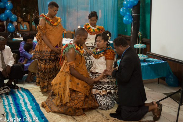 Niumaia and Nancy kneel with their pastor on woven mats as they receive the Traditional Fijian wedding rites.