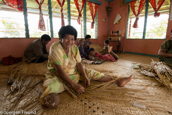 Fijian smile shines while the hands are busy weaving a kuta mat.