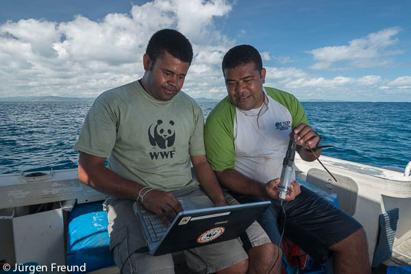 Laitia Tamata of WWF South Pacific and Laisiasa Cavakiqali of University of South Pacific downloads year-long data from the newly retrieved data logger that shows the temperature of the Great Sea Reefs for a year.